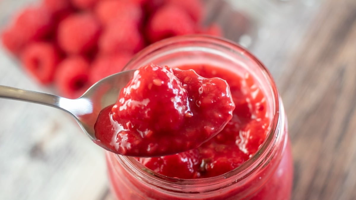 Wide image of raspberr pie filling in a glass jar.