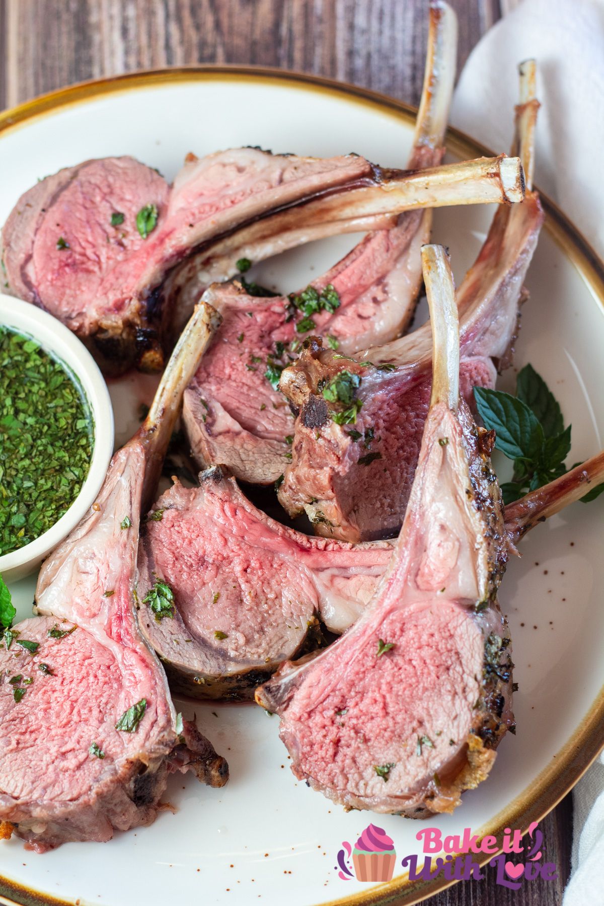 Tall image of lamb chops from the rack of lamb, on a plate with mint sauce.