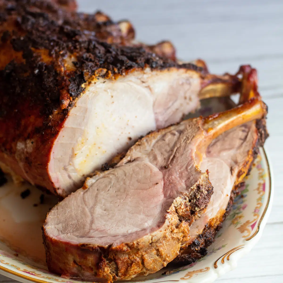 Immagine quadrata di carne di maiale affettata su un piatto da portata.