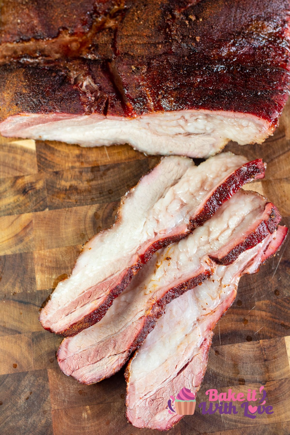Tall image of smoked pork belly sliced on a cutting board.