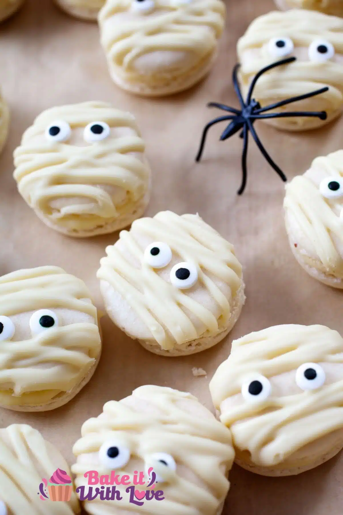 Halloween mummy macarons in a single layer with spider decorations.