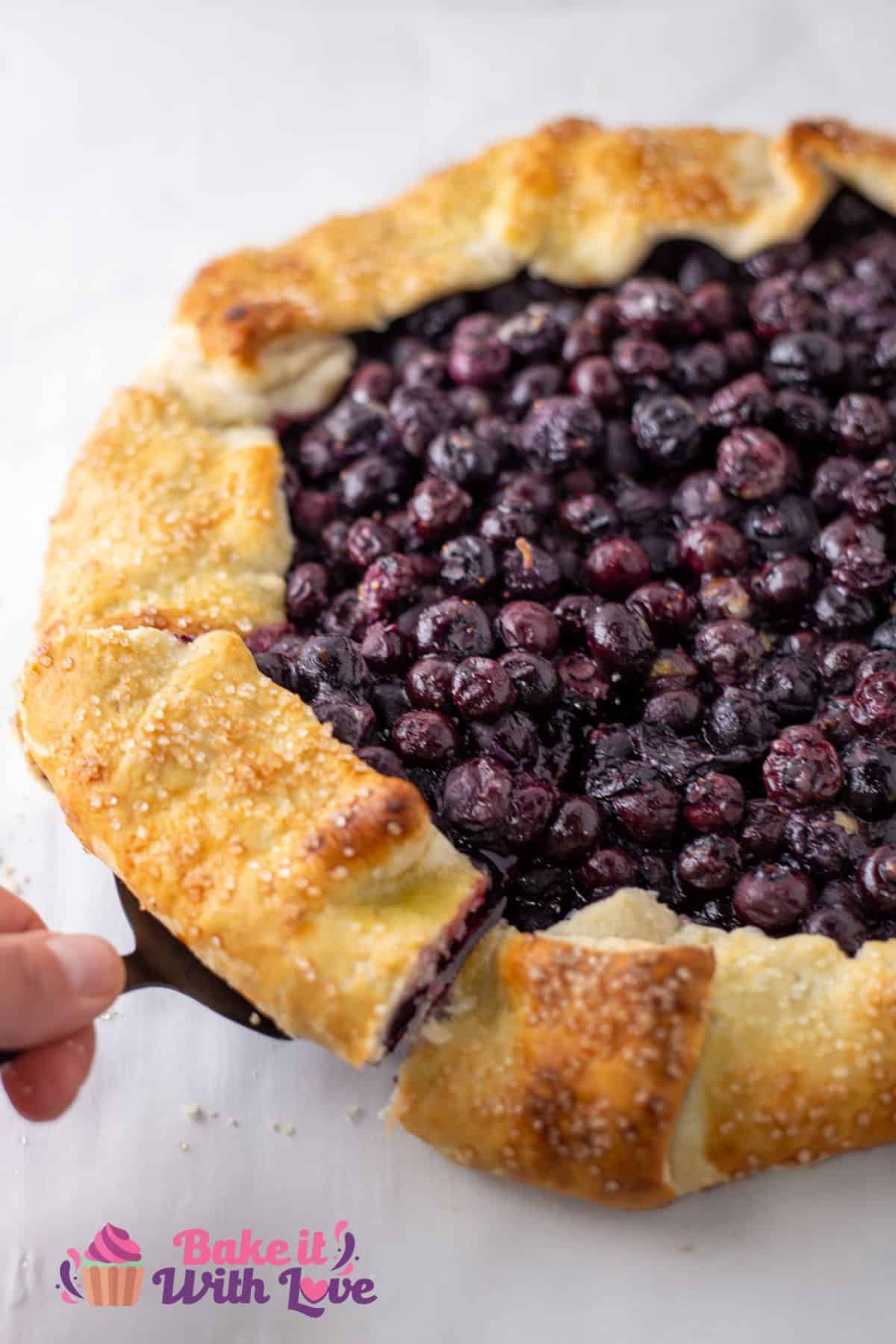 Baked blueberry galette slice being lifted away for serving.