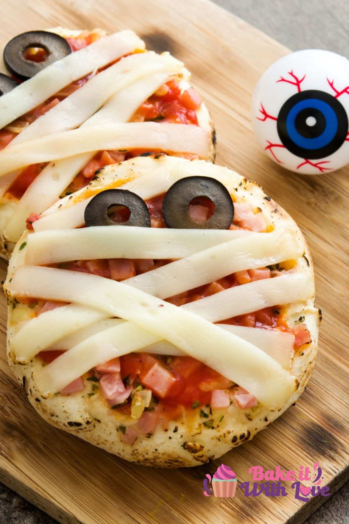 Easy to make mini mummy pizzas using English muffins, mozzarella strips, and sliced olives.