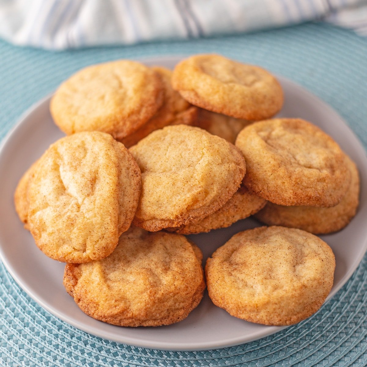 Best snickerdoodles without cream of tartar stacked on a white plate with light blue background.
