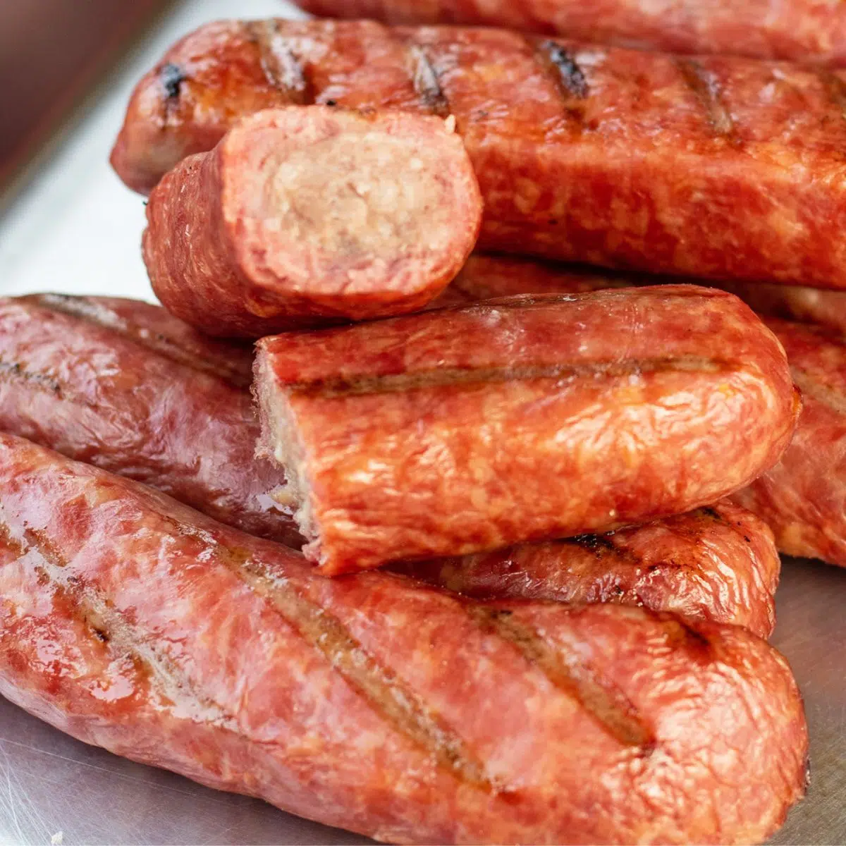 Što je bratwurst kobasica ilustrirana narezanim bratwurst kobasicama na metalnom pladnju.