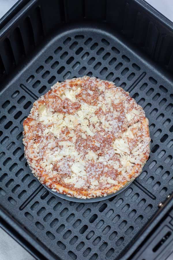 Process image 3 showing the frozen pizza in the air fryer basket before cooking.