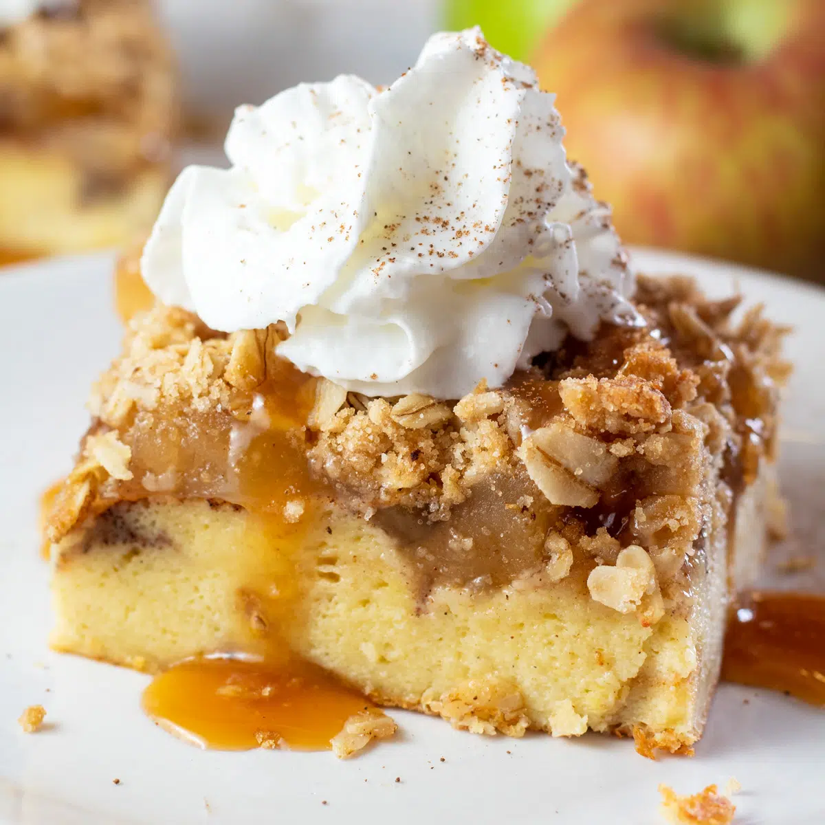 Immagine quadrata di una fetta di torta di mele French toast casseruola con panna montata in cima.