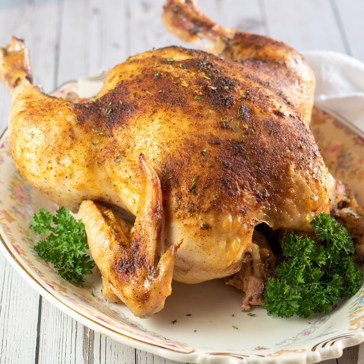 Čtvercový obrázek bage pečené kuře na talíři s petrželkou.