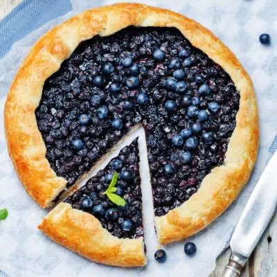 Square overhead image of blueberry galette with a slice cut out.