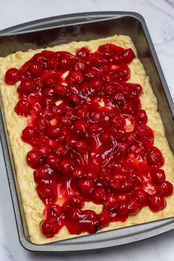 Process image 9 showing cherry pie filling on dough in baking pan.