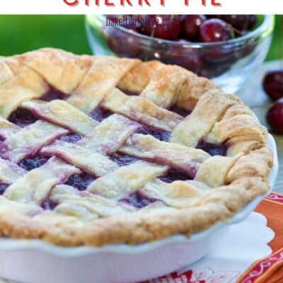 Pin image of a cherry pie with cherries in the background.