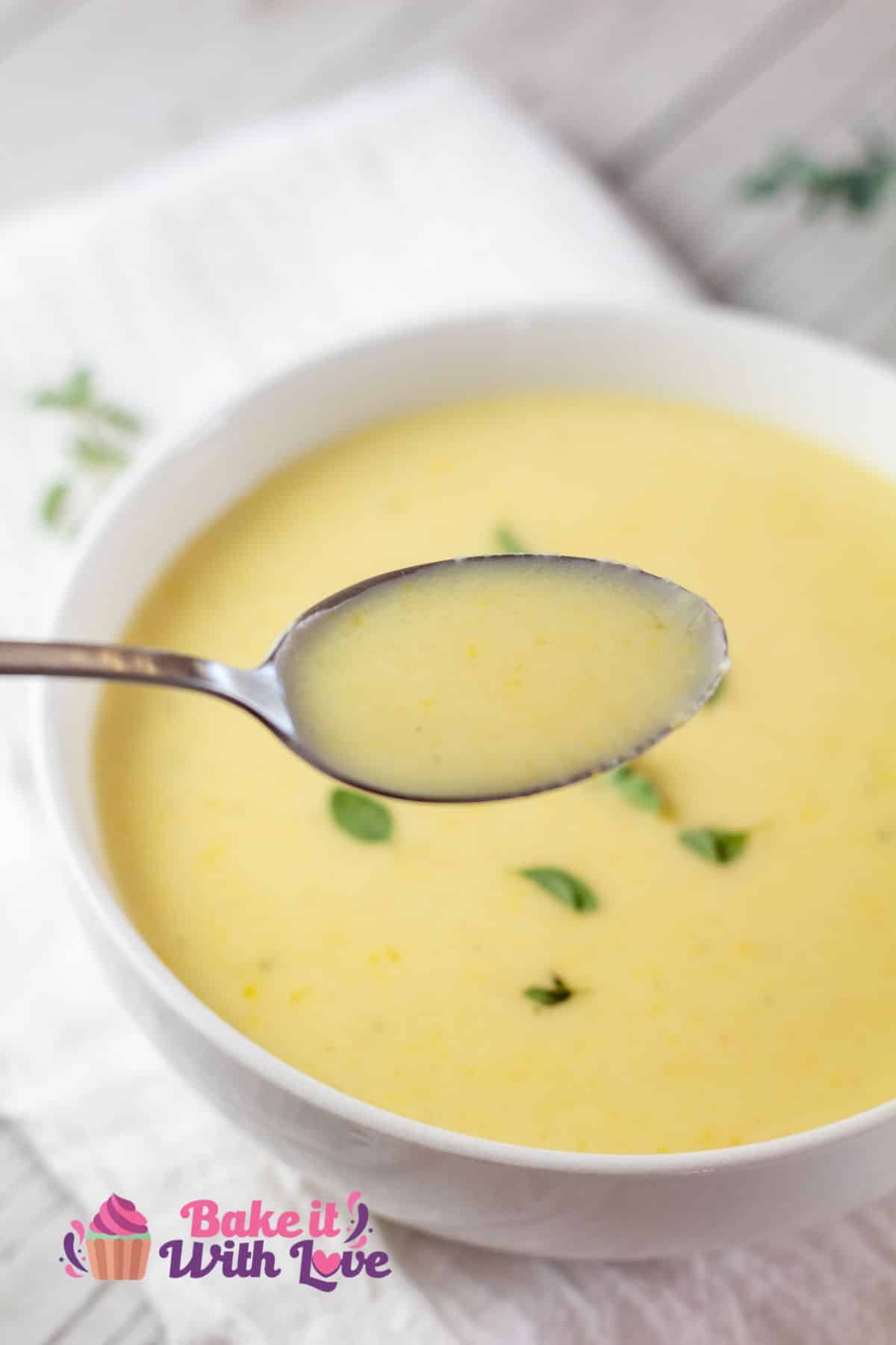 Tall image of creamy yellow squash soup in a white bowl.