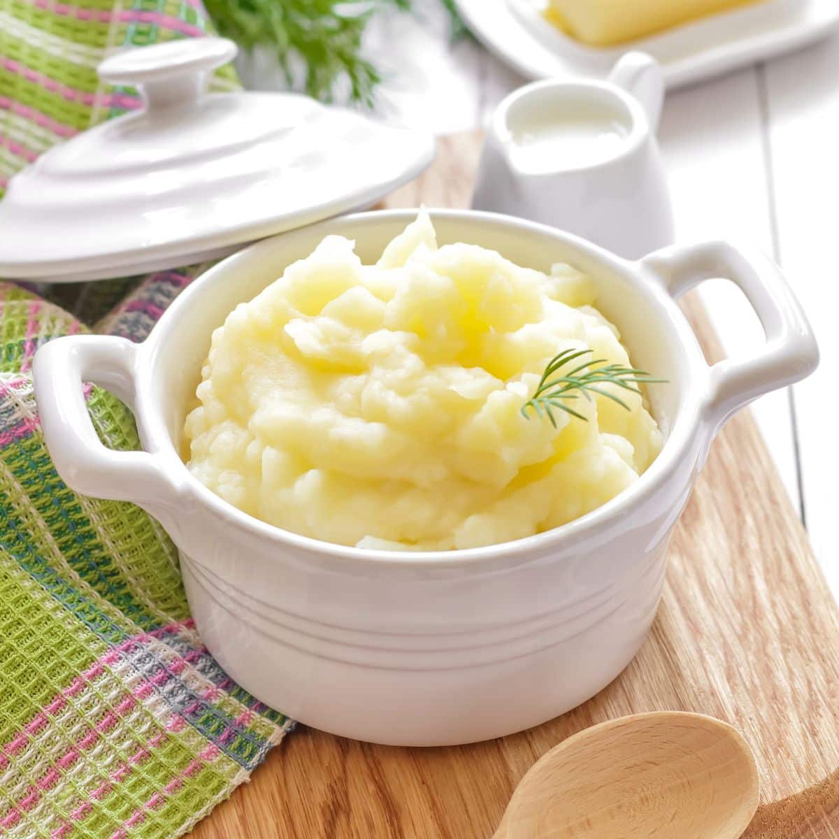Kvadratna slika pire krumpira u bijeloj zdjeli za kuhanje.