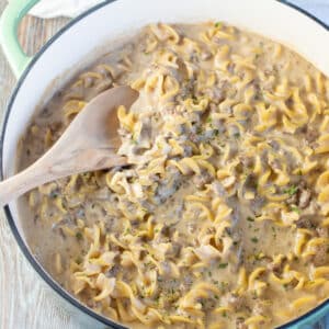 Square image of hamburger helper beef stroganoff in a large pan with wooden spoon.