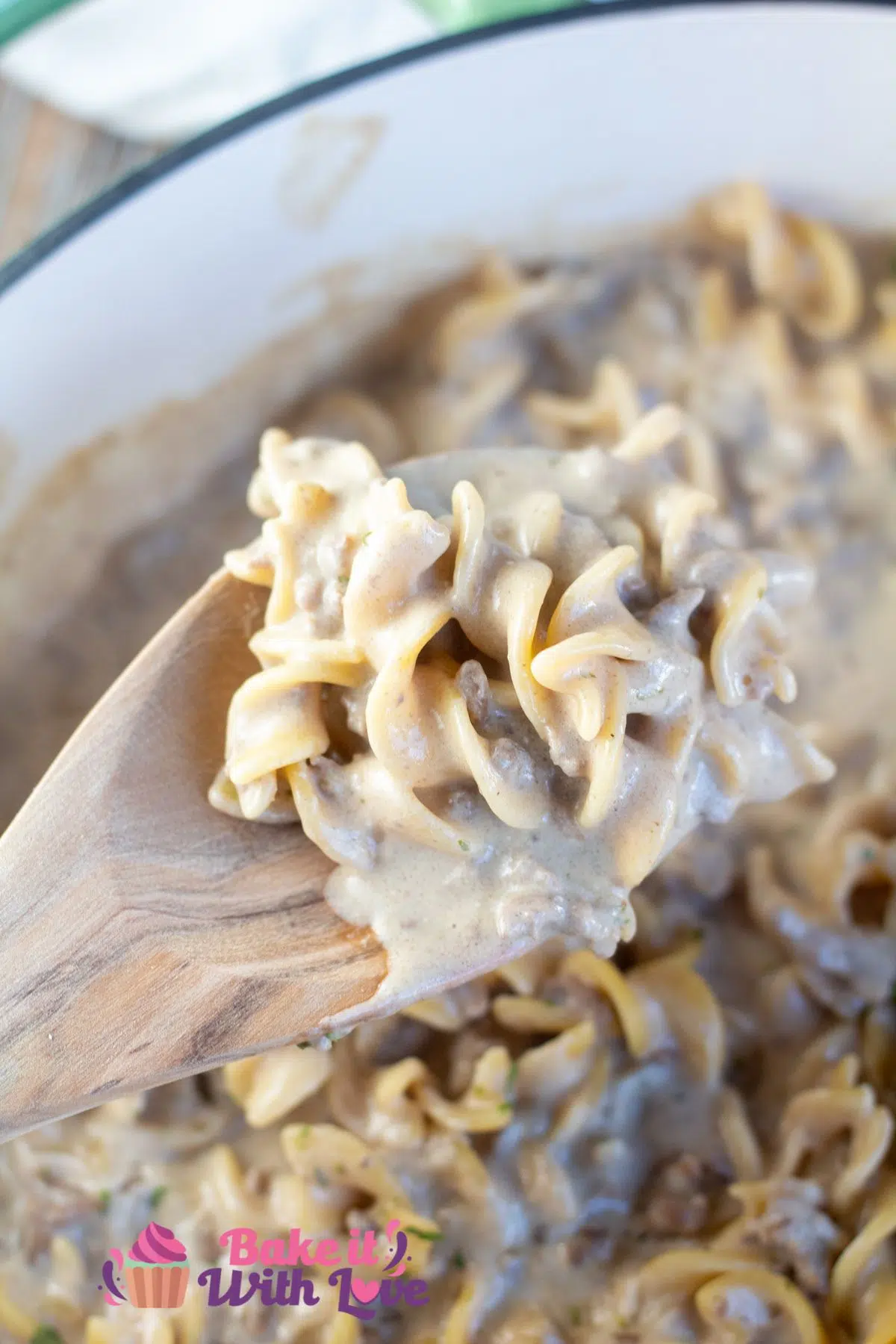 Tall image of hamburger helper beef stroganoff in a large pan with wooden spoon.