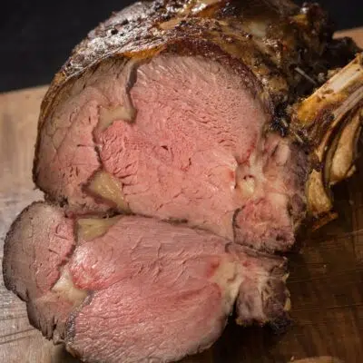 Square image of prime rib on a cutting board.