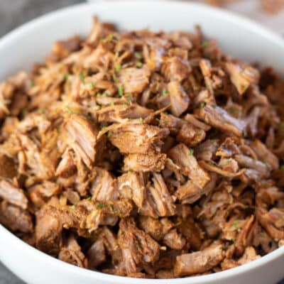 Square image of instant pot pulled pork in a white bowl.