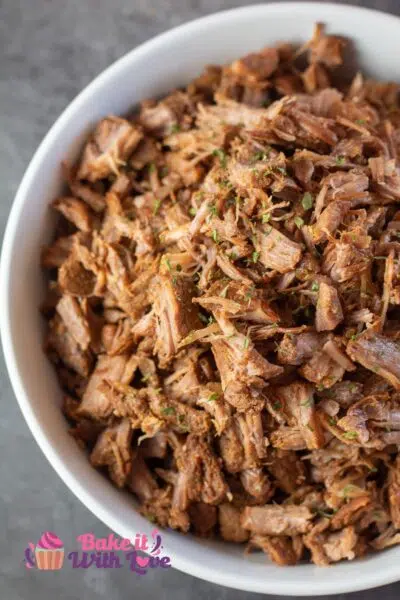 Tall image of instant pot pulled pork in a white bowl.