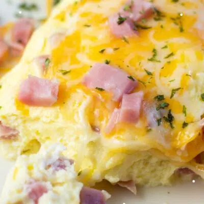 Pin image with text of an omelet on a plate with ham & cheese.