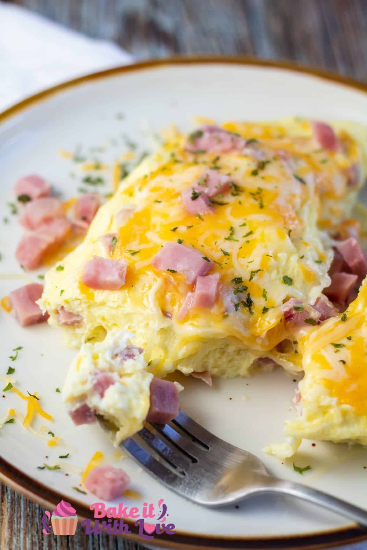 Tall image of an omelet on a plate with ham & cheese.