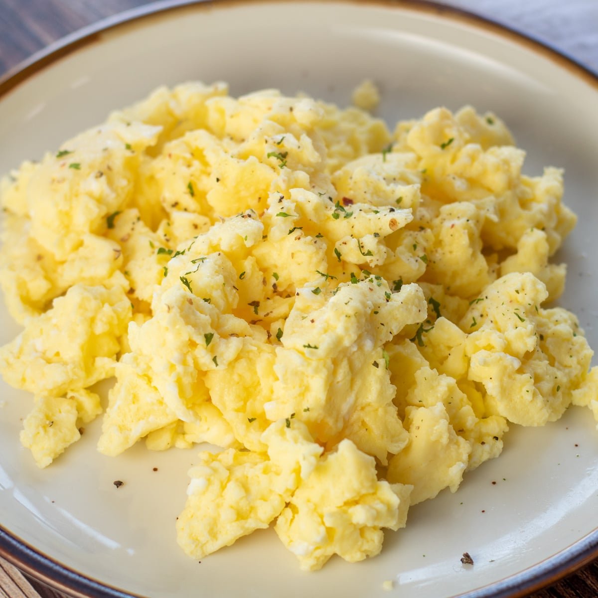 Square image of microwaved scrambled eggs on a plate.