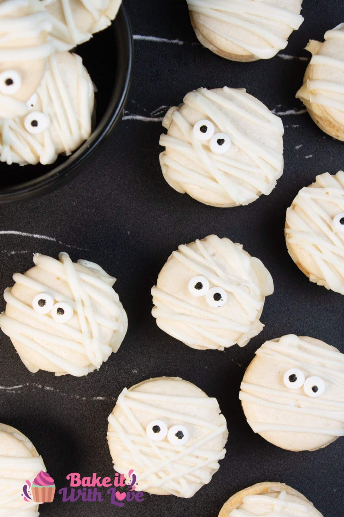 Tall overhead image of the decorated mummy macarons on black background.