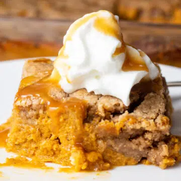 Wide image of a slice of pumpkin dump cake on a white plate.