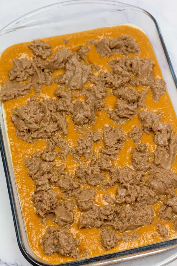 Process image 6 showing combined cake ingredients on pumpkin mix in baking dish.