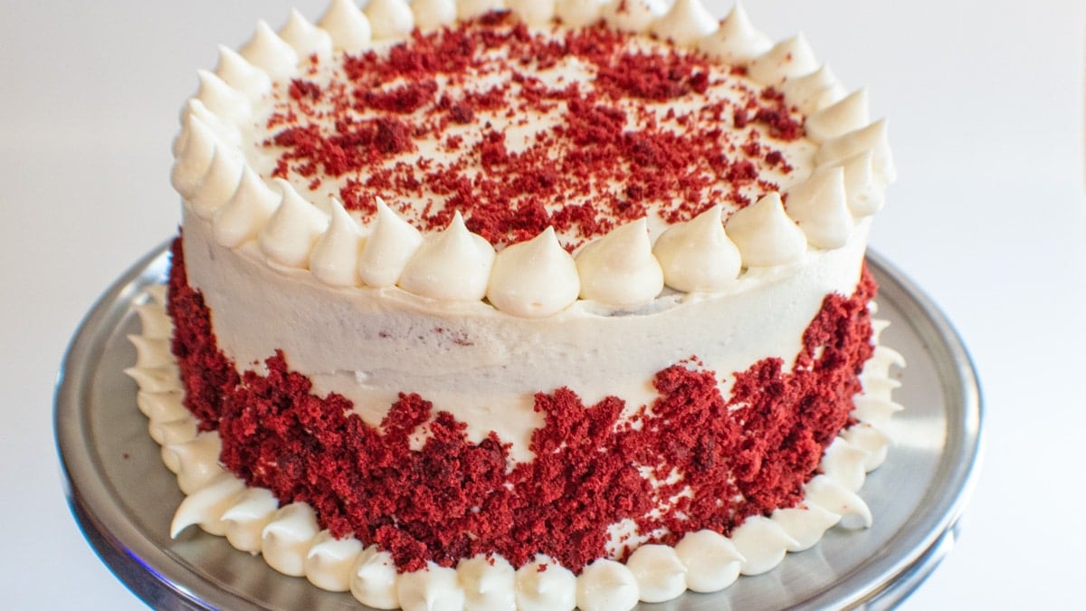 Široký obraz červeného sametového dortu s polevou ze smetanového sýra.