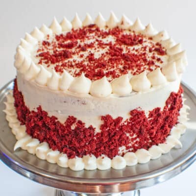 Square image of red velvet cake with cream cheese frosting.