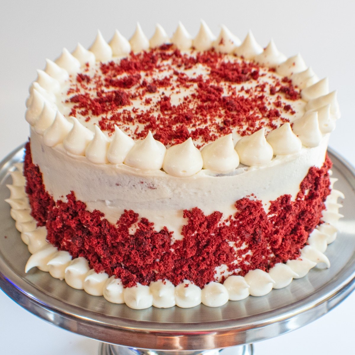 Vierkant beeld van red velvet cake met roomkaas frosting.