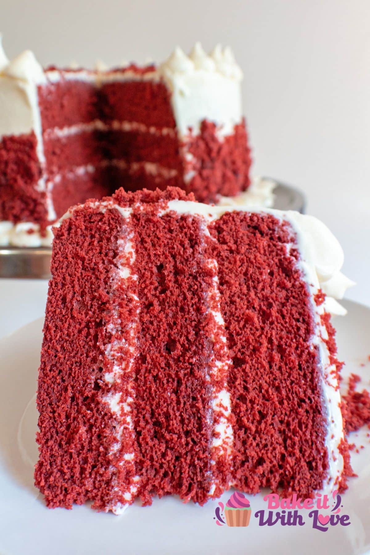 Tall image of red velvet cake with cream cheese frosting.