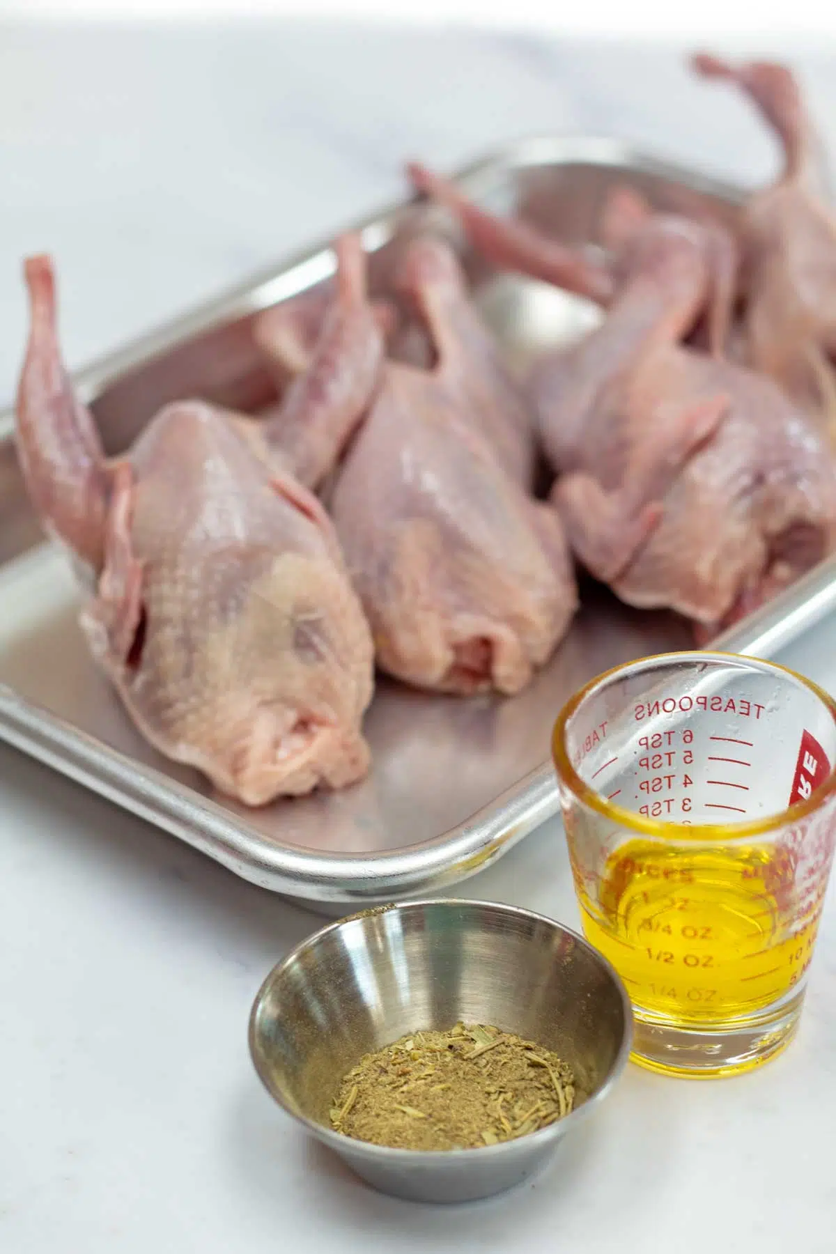Tall image showing ingredients needed for roasted quail.