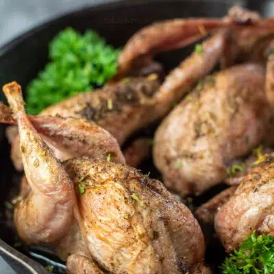 Pin image with text of roasted quail in a cast iron pan with parsley.