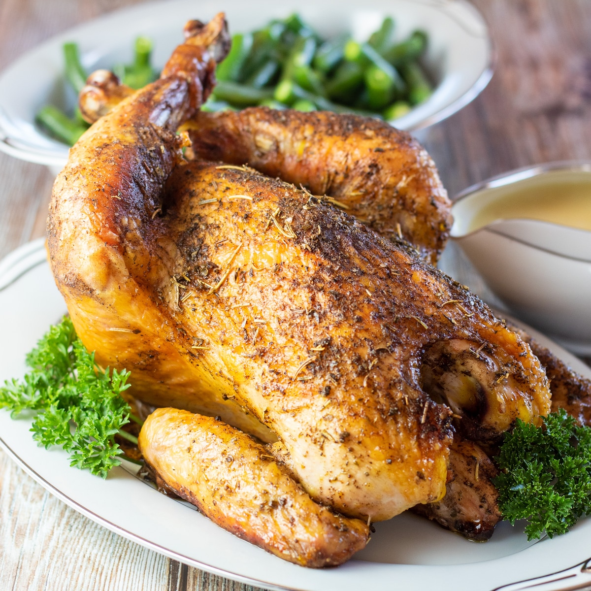 Square image of roasted sasso chicken on a serving dish.
