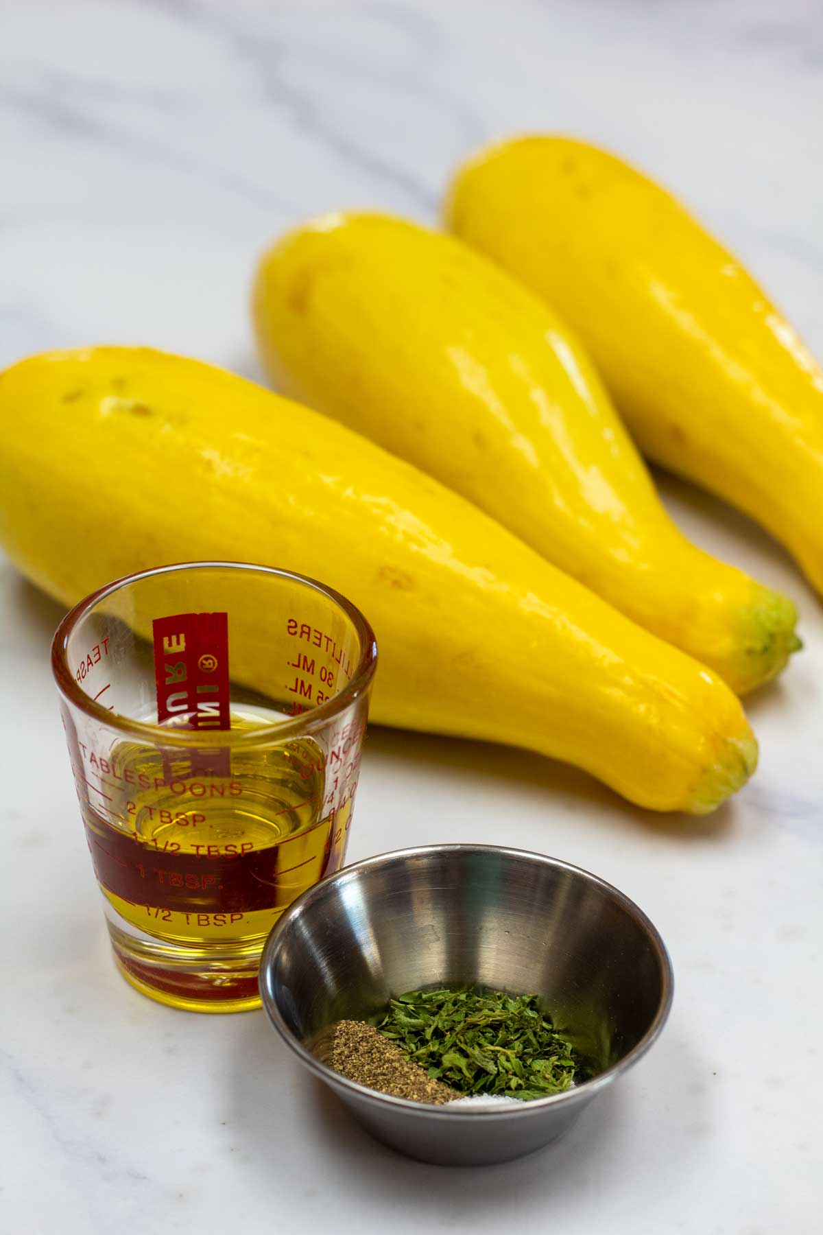 Tall image showing ingredients for sauteed yellow squash.