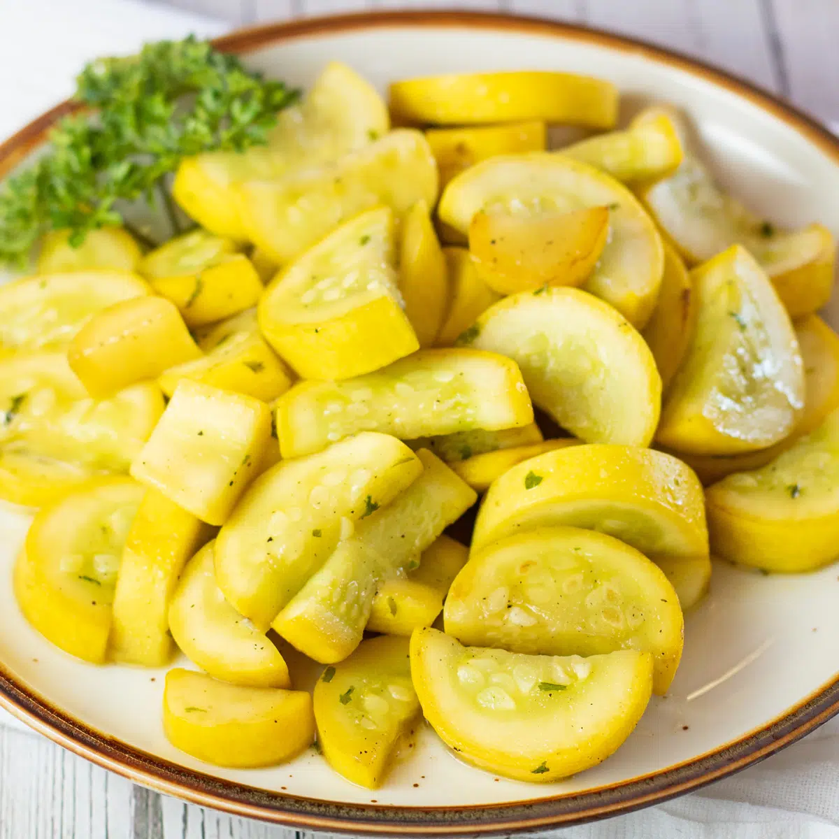 Square image of a plate with sauteed yellow squash.