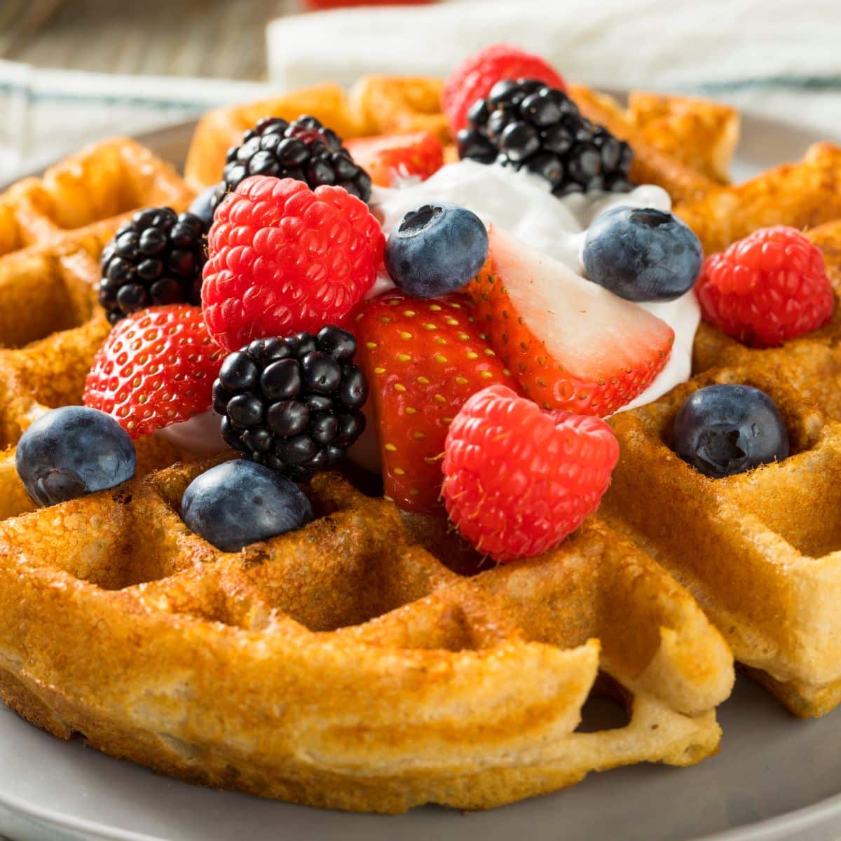 Square image of waffles with fruit on top.