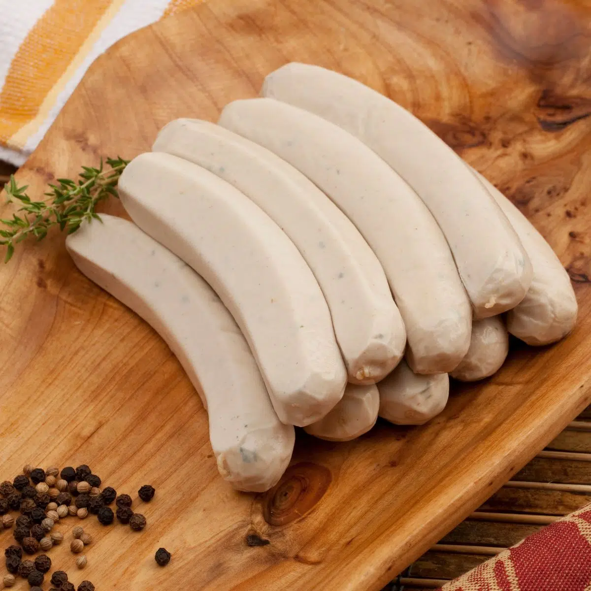 O que é salsicha bockwurst ilustrado com bockwursts empilhados na tábua de madeira.