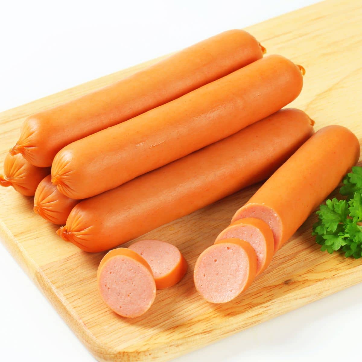 What is frankfurter illustrated with stacked frankfurters on light wooden cutting board.