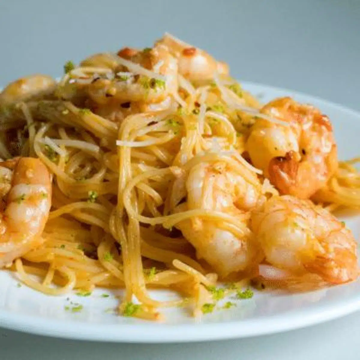 Square image of bang bang shrimp pasta on a white plate.