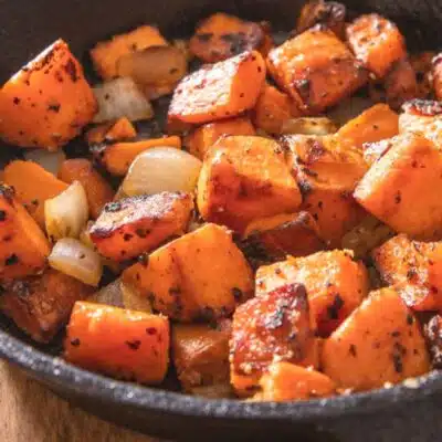 Square image of pan fried sweet potatoes in a cast iron pan.