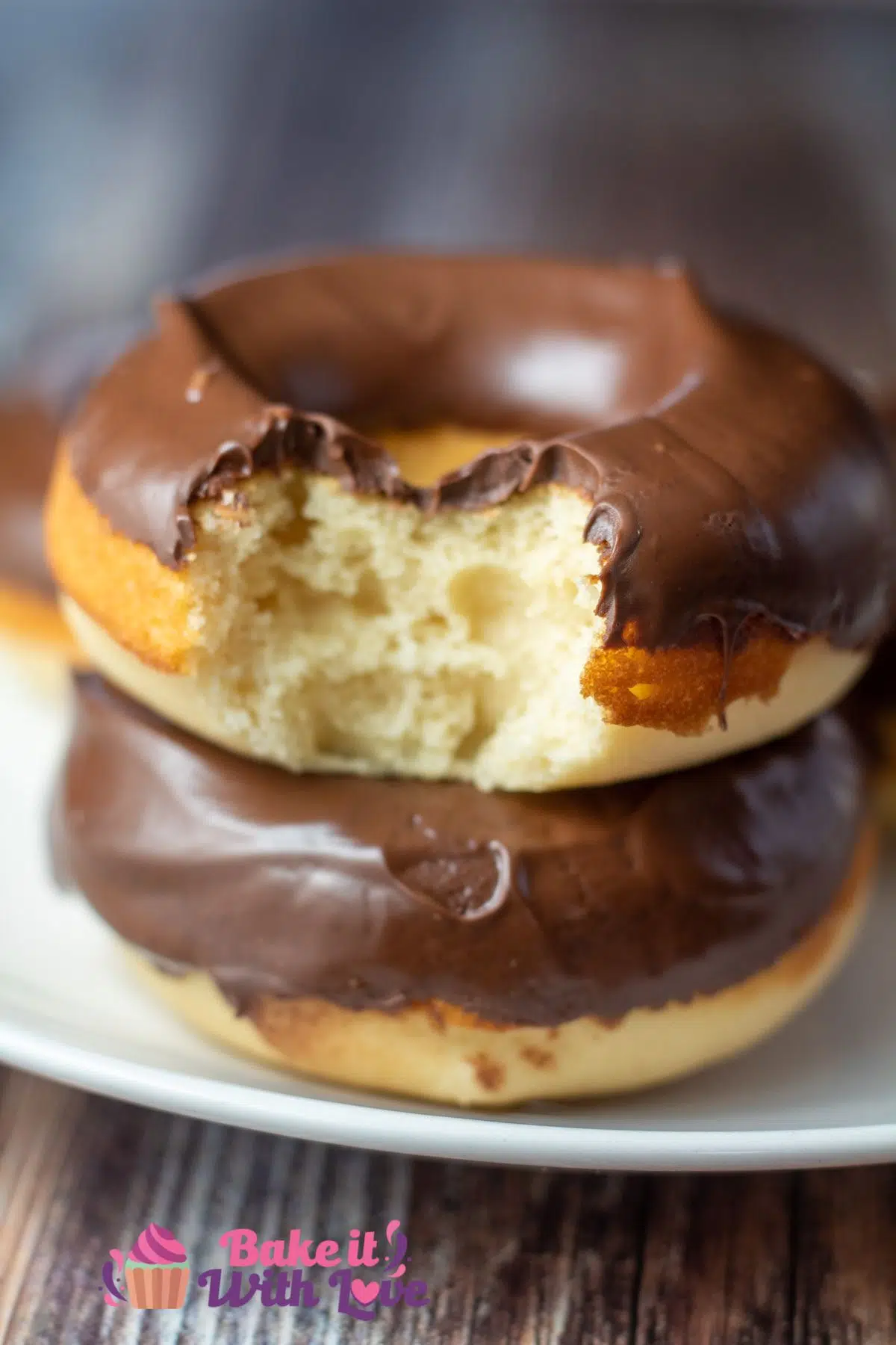 Tall image of chocolate fosted baked donuts on a white plate.