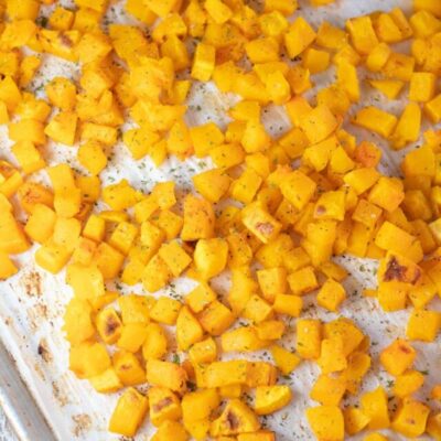 Tall image of roasted butternut squash on a baking sheet.