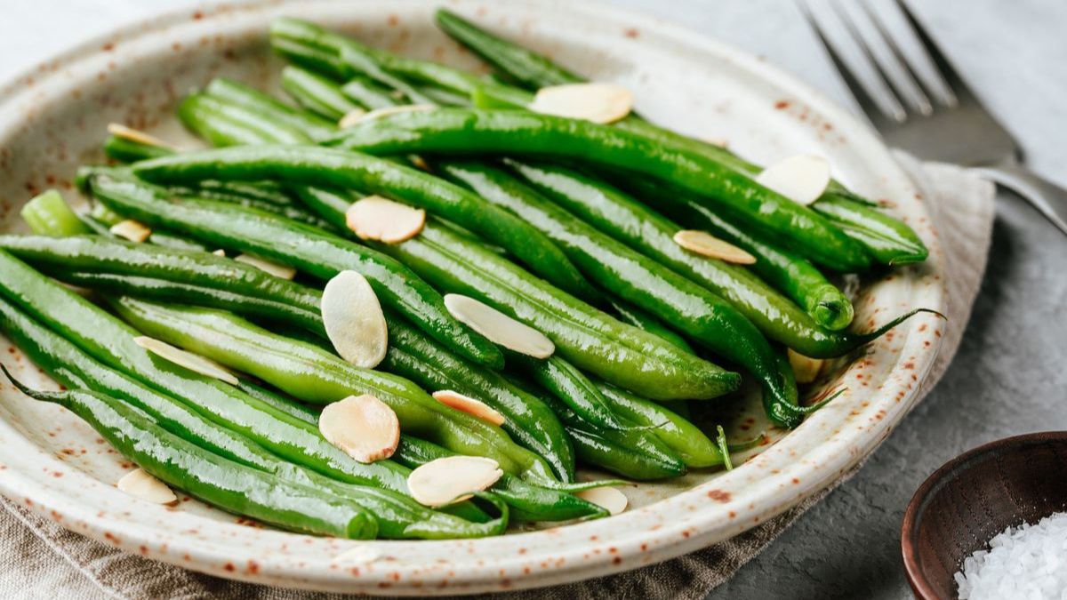 Wide image of green beans almondine on a serving platter.