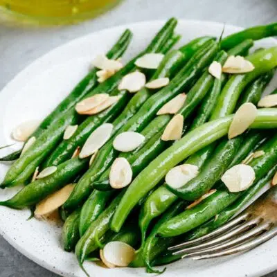 Square image of green beans almondine on a serving platter.