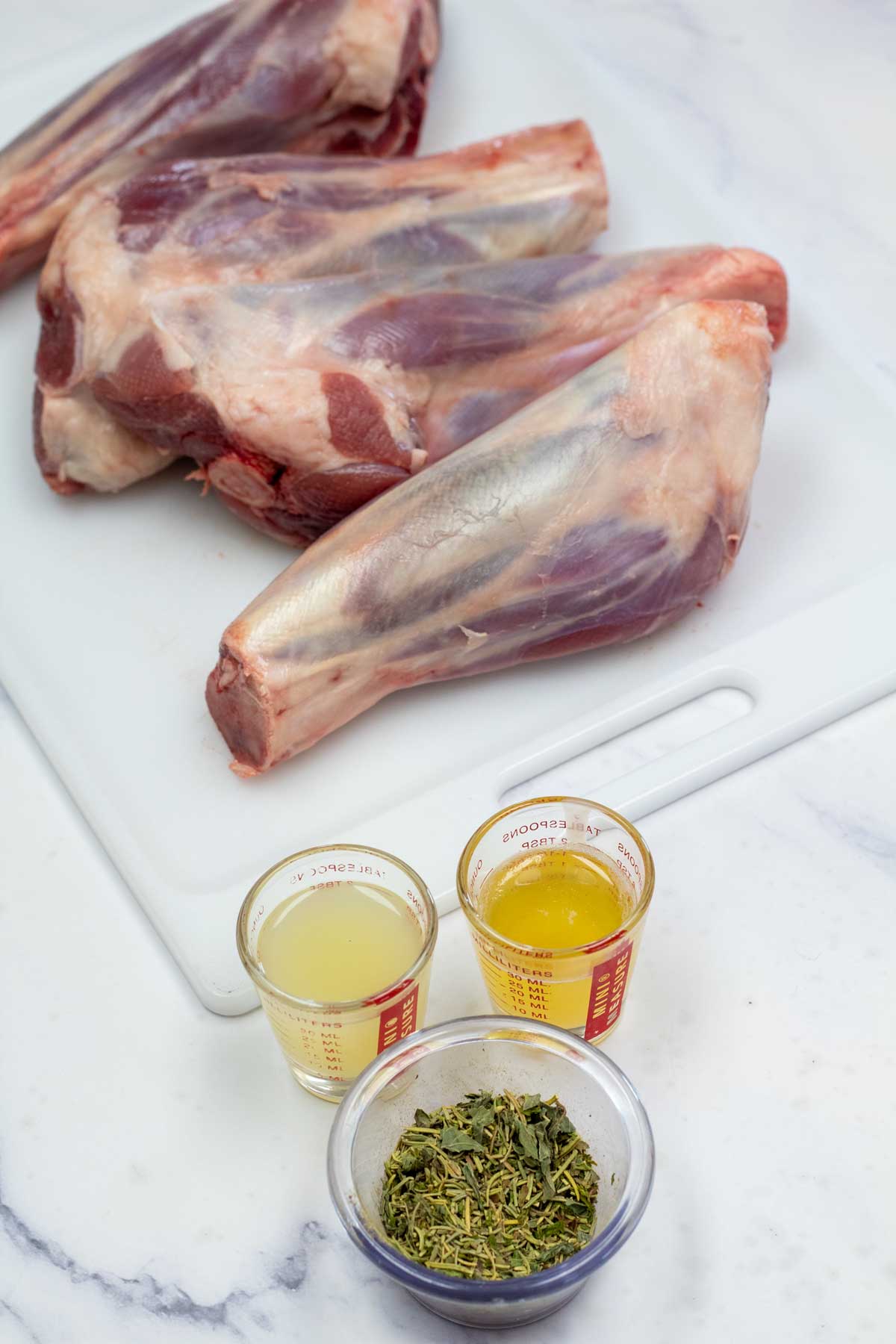 Tall image showing the ingredients needed for grilled lamb shanks.