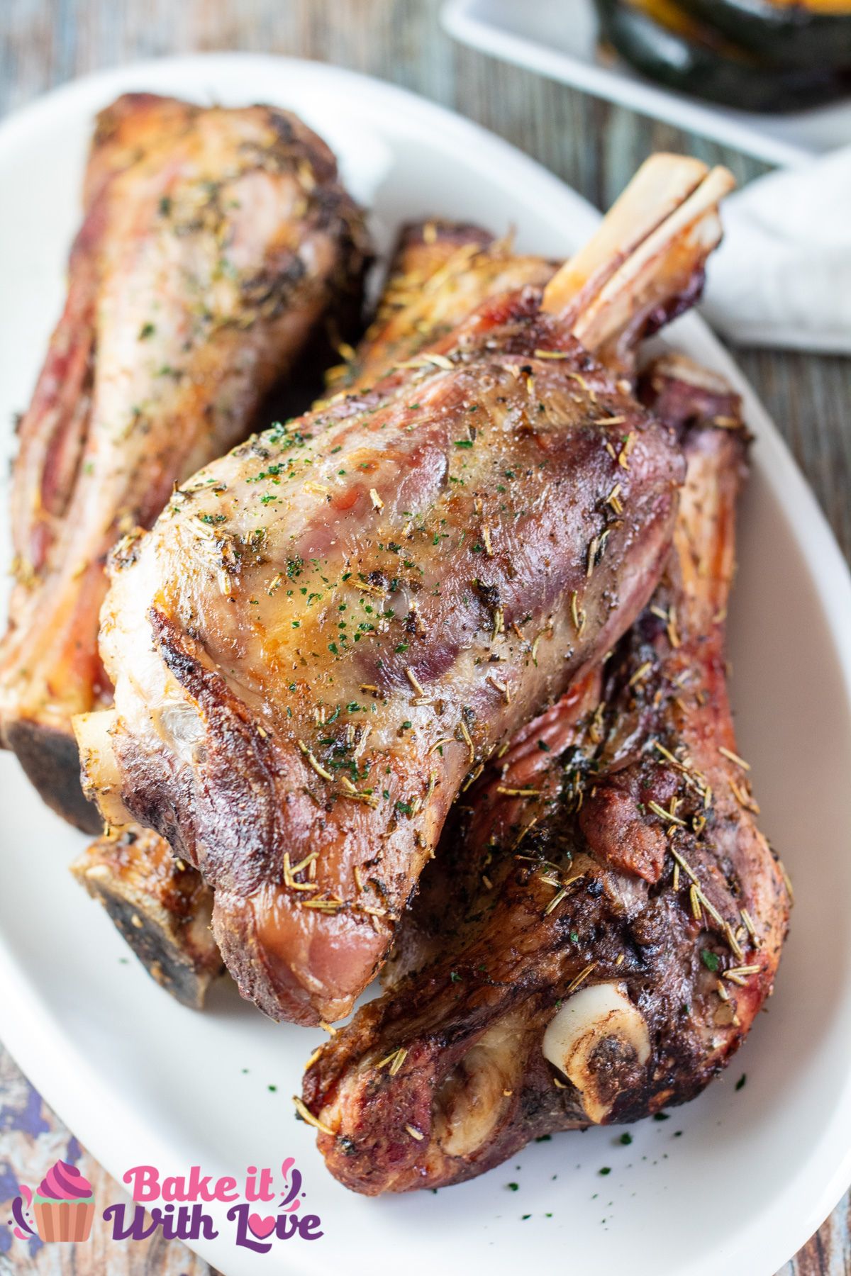 Tall image of a white serving platter with grilled lamb shanks.