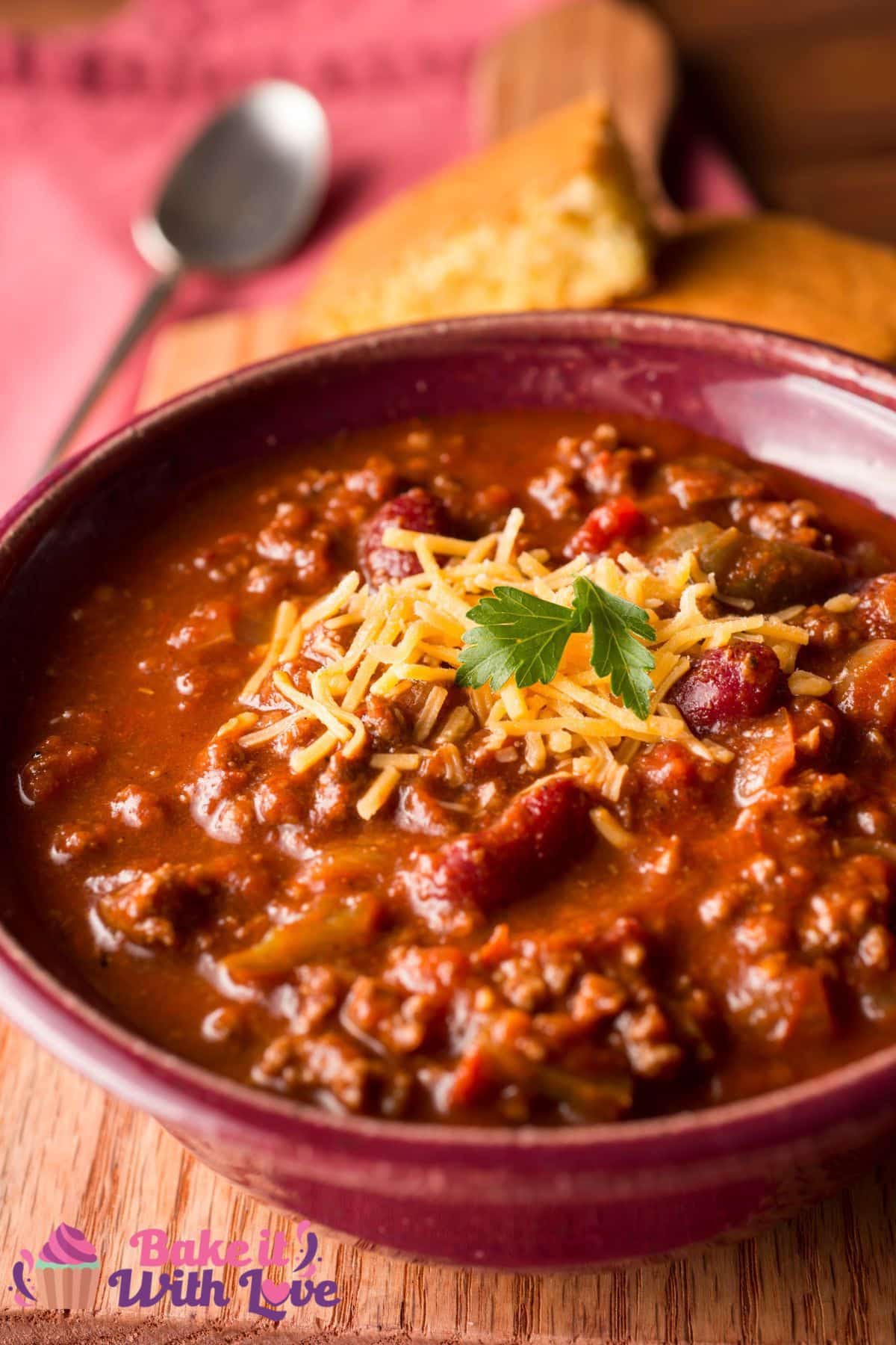 Tall image of the dished up homemade chili in maroon bowl.