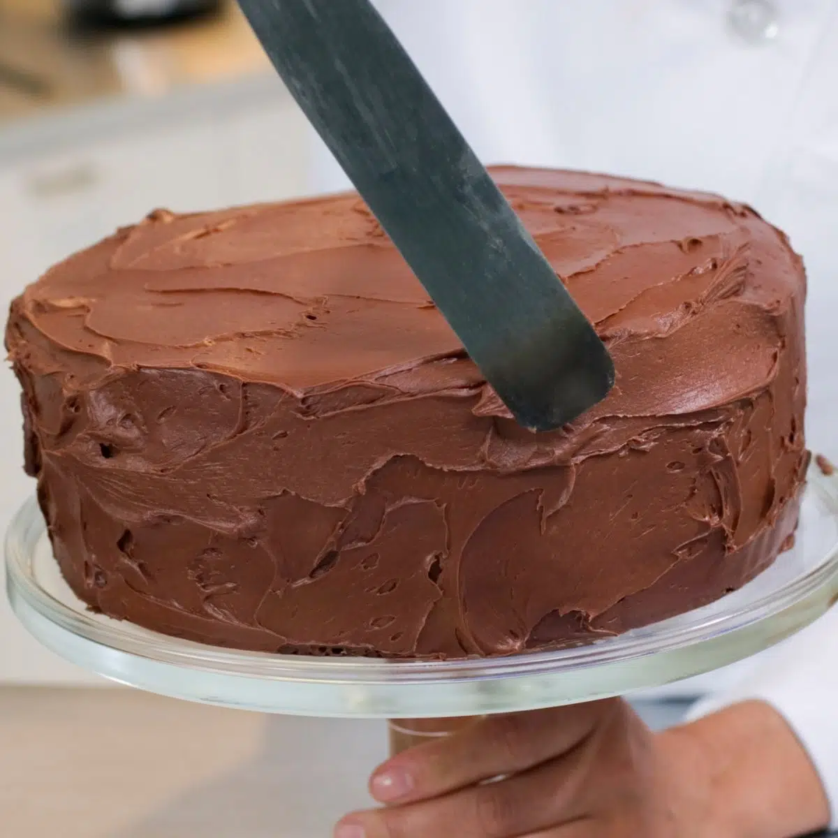 Square image showing frosting a cake.